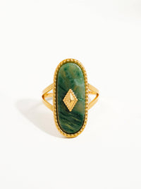 Front view of a gold ring with a green marbled oval stone centerpiece, bordered by beaded detailing and a geometric accent