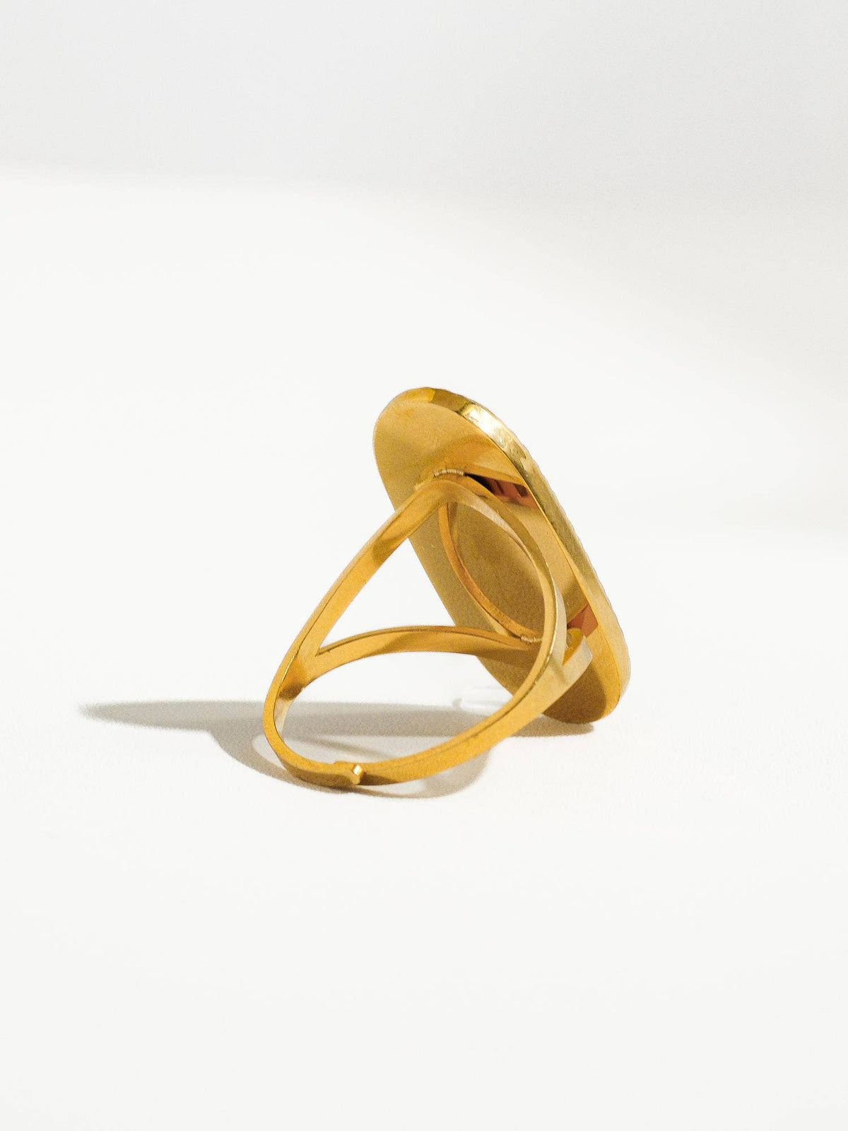 Side view of a gold ring with a slim band and a statement oval-shaped setting, showcasing its elegant craftsmanship