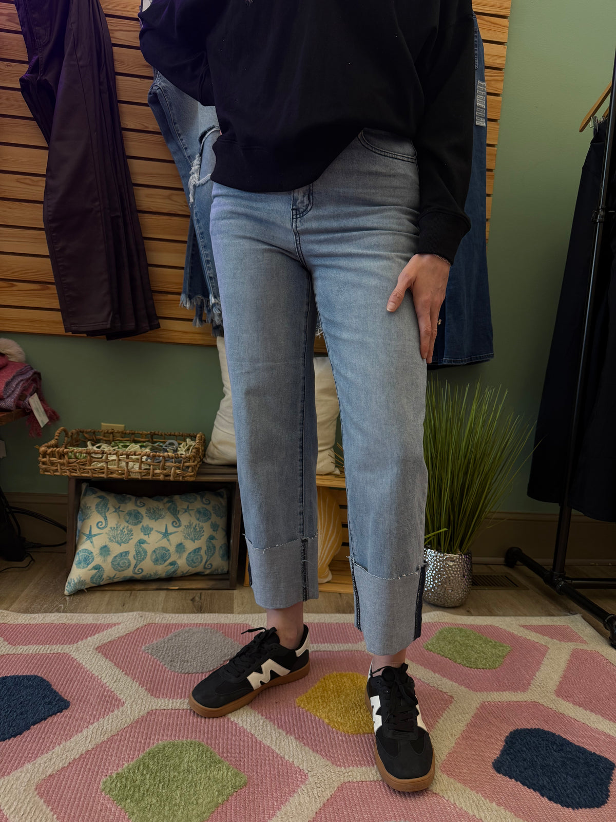 Front view of light denim straight-leg boyfriend jeans with a high-waisted fit and cuffed hem, paired with a black sweatshirt and casual sneakers.