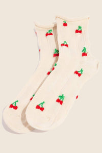 Pair of beige socks with cherry embroidery displayed flat, highlighting the playful cherry pattern and the soft, ribbed texture.