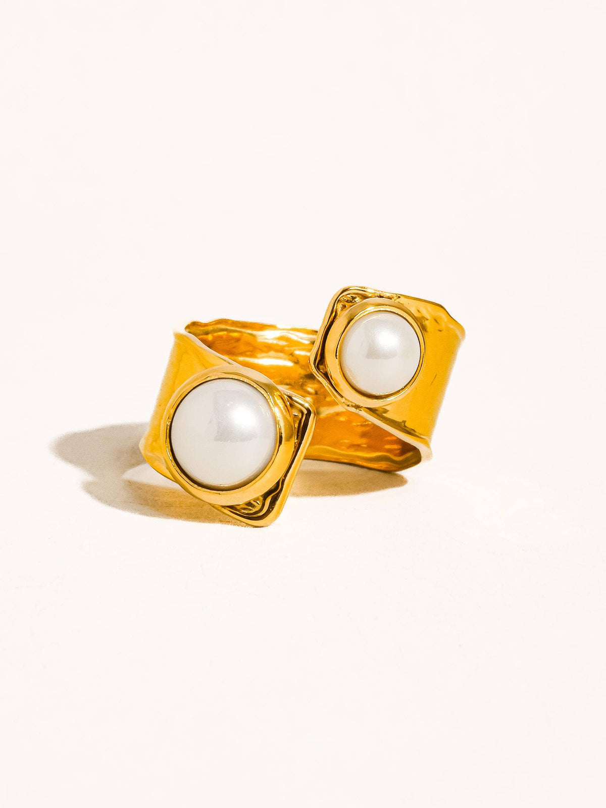 Close-up of a gold statement cuff ring with a textured design and dual pearl accents, perfect for a sophisticated look.