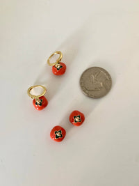 Tomato hoop earrings placed next to a quarter for size comparison.