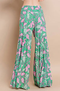 Back view of boho wide-leg palazzo pants with smocked waist and bold paisley print in green, pink, and white.