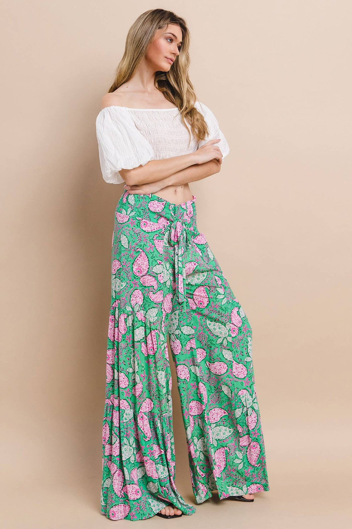 Model wearing boho palazzo pants styled with a white off-shoulder crop top, exuding a relaxed, resort-ready look.