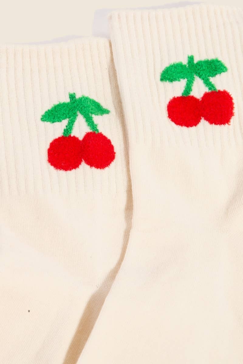 A close-up of the top of two beige socks showcasing the intricate red cherry embroidery with green stems on the ribbed cuff.