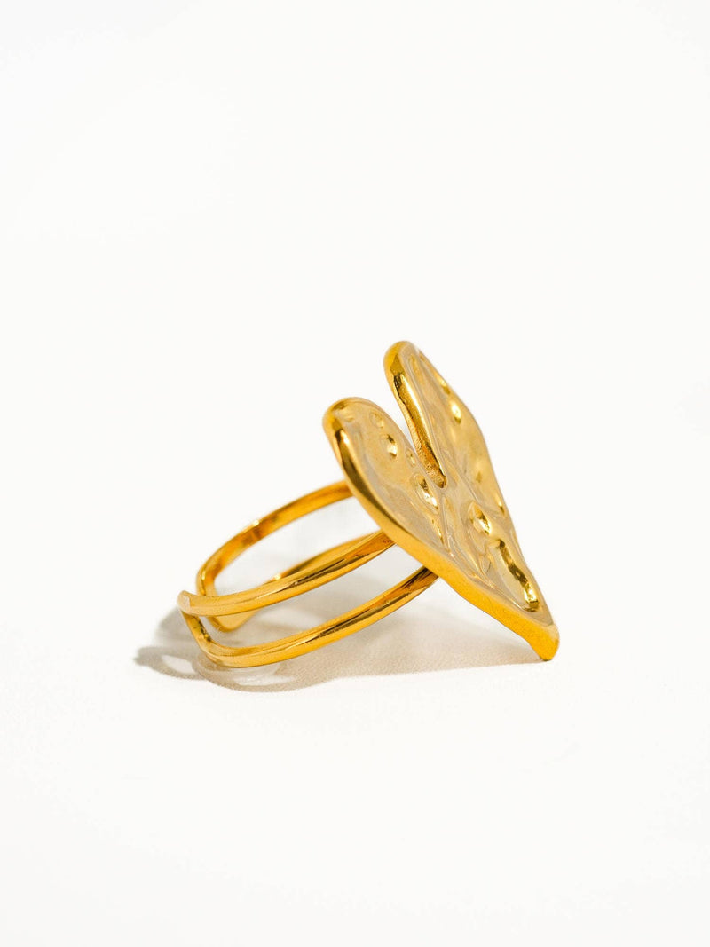 A detailed side angle of the gold ring with a double band and a heart-shaped centerpiece, highlighting the texture and craftsmanship of the design.