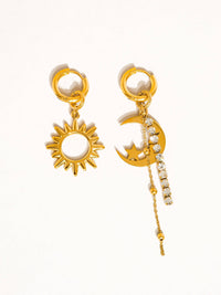 Pair of mismatched celestial earrings with a gold sun charm and a crescent moon with sparkling rhinestone chains, perfect for a chic and unique look