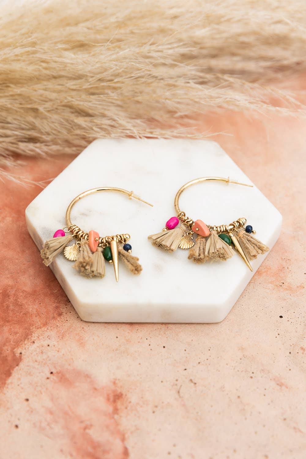 coastal chic hoop earrings with beads and shells and tassels on a display stand
