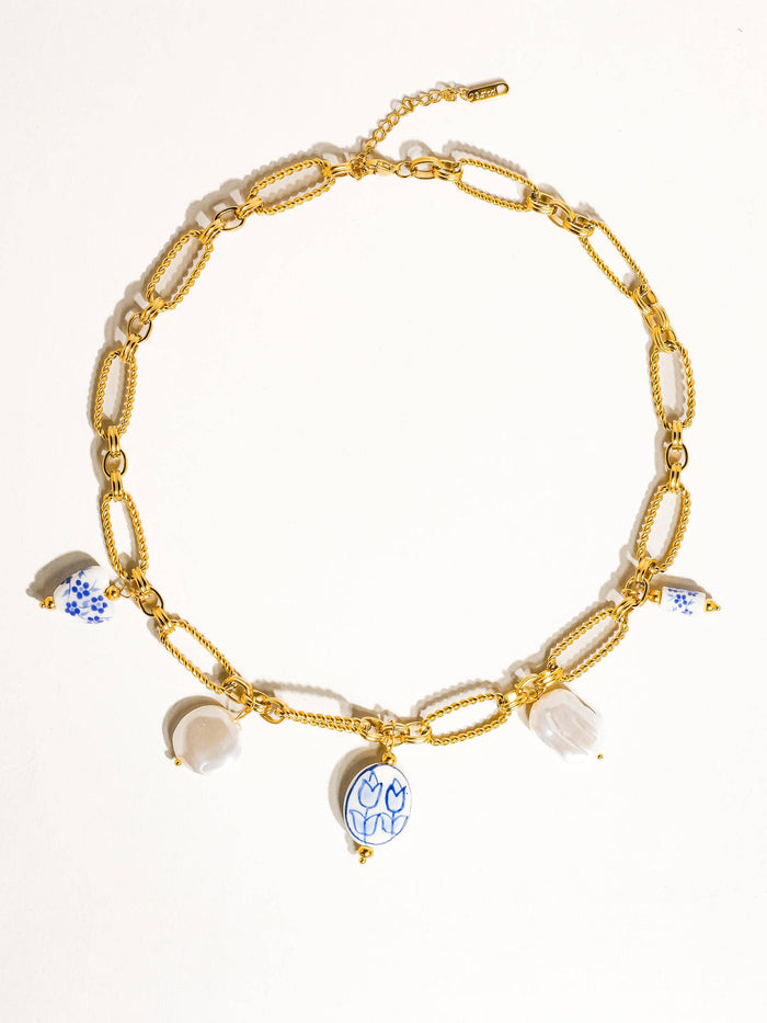 Full view of a gold chain necklace with ceramic tulip and floral charms, white bead details, and an elegant adjustable clasp