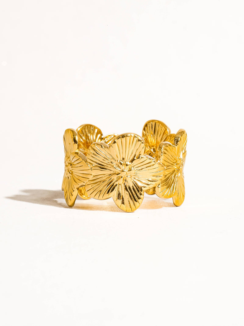 Gold floral ring with intricately carved petals, displayed upright