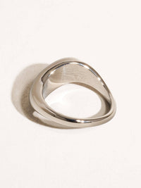 Close-up of a minimalist silver statement ring with a smooth, curved design, showcasing its modern elegance.