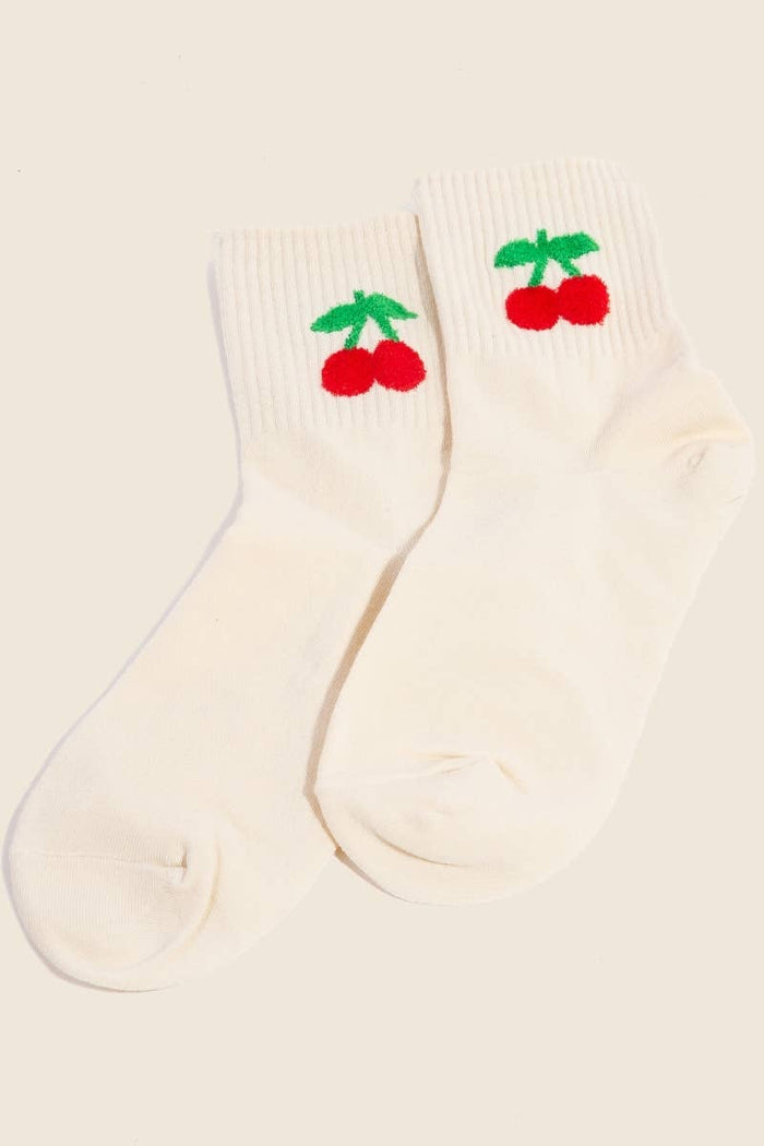 A pair of beige socks featuring red cherry embroidery with green stems, laid side by side on a neutral background.