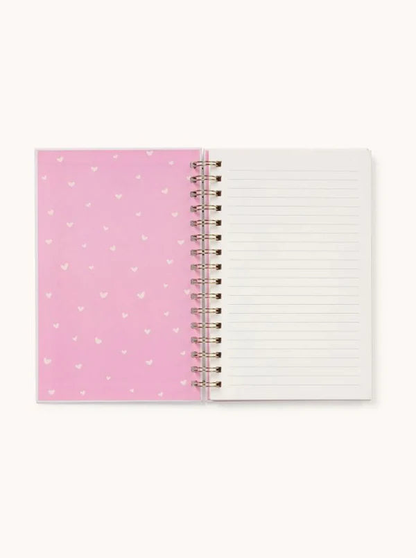 Inside view of the notebook showing lined pages and a pink heart-patterned cover.