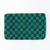 The back of the beaded clutch, displaying a bold kelly green and navy checkered pattern, intricately handwoven for a stylish and graphic look.